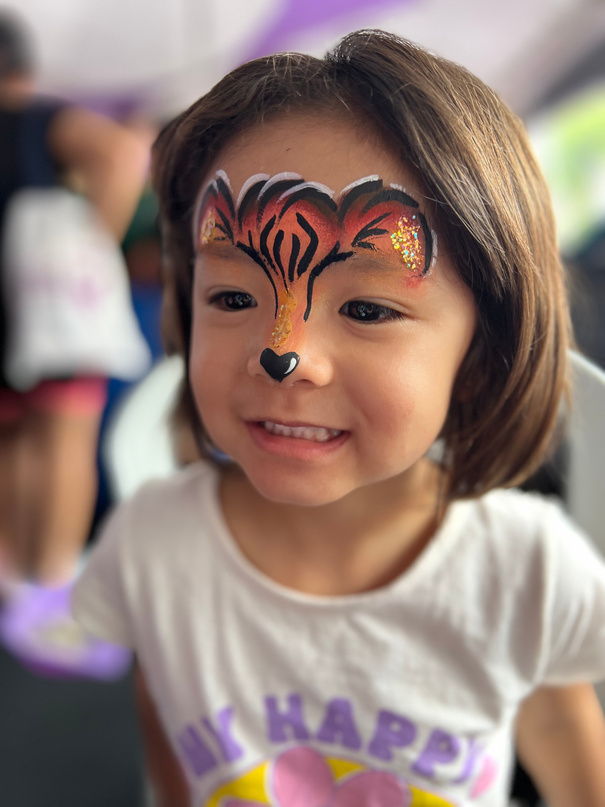 Menina com pintura facial de tigre feita por maquiadora profissional
