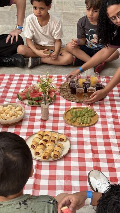 Mesa de piquenique com toalha xadrez, frutas e salgados