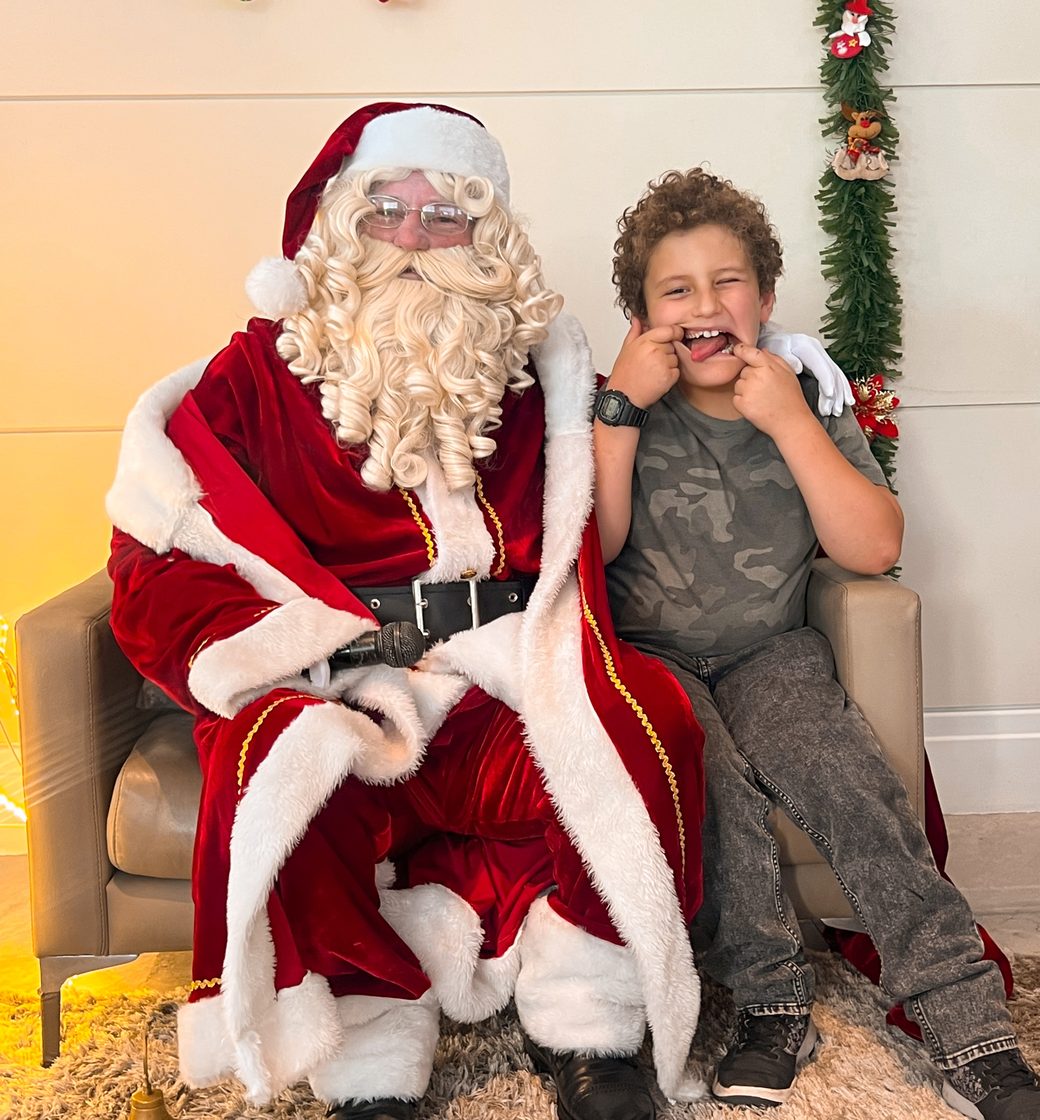 Papai Noel recebendo uma criança na ação de fim de ano da Colors Lazer
