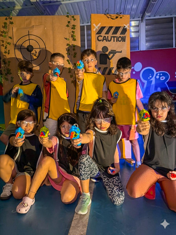 Crianças de colete amarelo em campo de Guerra Nerf montado pela Colors Lazer