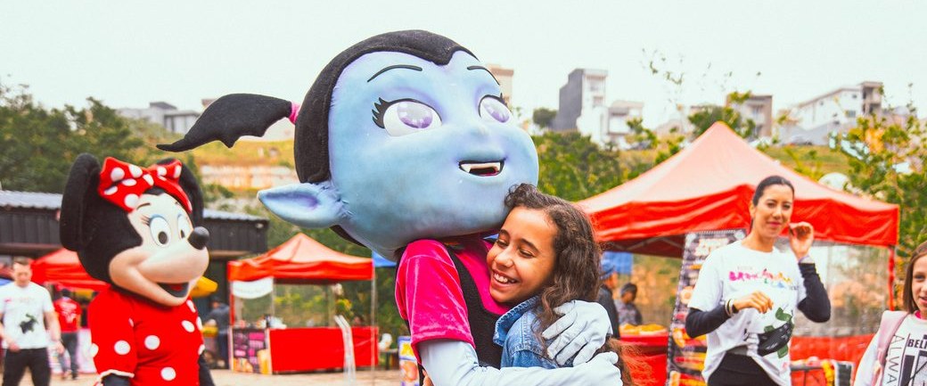 Personagem da Colors Lazer abraçando uma criança em um Kids Day de empresa