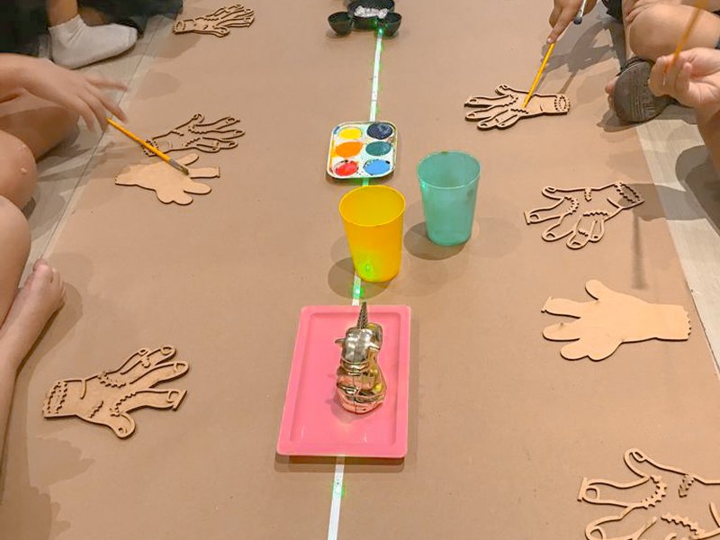 Bancada de oficina com tintas, pincéis e peças de madeira para pintar