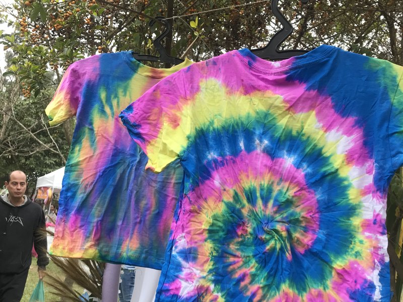 Camiseta tingida em tie-dye pendurada para secar depois da oficina
